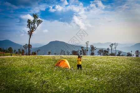 山丘上的帐篷区露天营帐篷与旅游行者一起在森林的田野上与旅游者一起拍照在清晨美丽的天然绿草地拍照图片