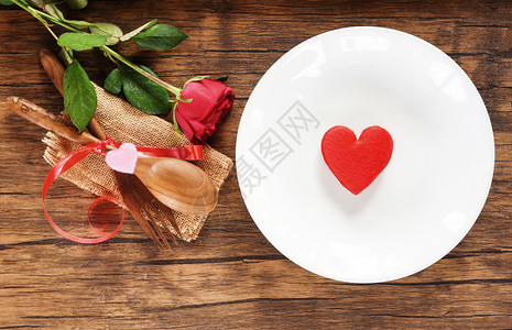 情人晚餐浪漫的爱和烹饪概念红心在白色盘子的浪漫桌上设置装饰用木勺叉子和玫瑰在生锈背景上图片