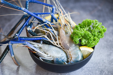 碗虾生新鲜配有香料柠檬绿用于在海产食品餐馆黑底烹饪图片