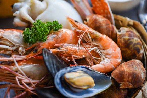 烹饪蒸汽食品为海鲜自助餐概念提供了服务新鲜虾鱿鱼贝发现盘底有比伦贝壳蟹和海鲜酱柠檬图片