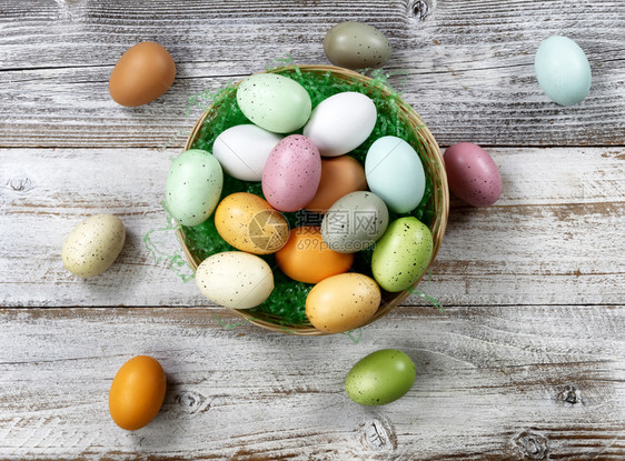 复活节快乐概念在白锈木上装满一篮彩色鸡蛋图片