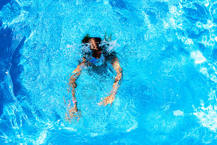 女孩在暑假期间阳光下她的私人游泳池里潜水图片
