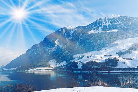 美丽的冬季湖泊雪山和耶稣光太阳图片