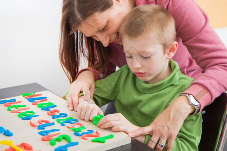 在冠状检疫期间母亲和她的小男孩玩彩色造型粘土游戏背景图片