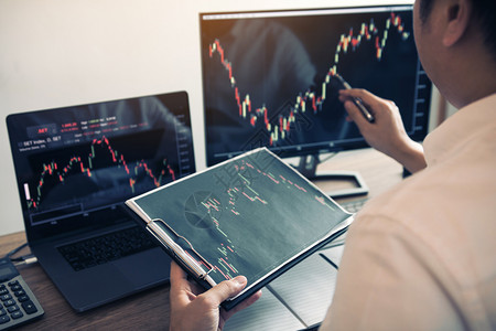 投资者用笔指向电脑屏幕分析股市图背景图片