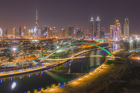 宽容桥和迪拜市中心天线的空观测夜间与湖泊或河流阿拉伯联合酋长国或阿金融区和城市商业的建筑结构图片
