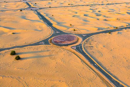 在迪拜市阿拉伯联合酋长国或阿拉伯联合酋长国日落时自然景观背下环形半沙漠公路或丘街道的空中观察图片