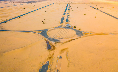 在迪拜市阿拉伯联合酋长国或阿拉伯联合酋长国日落时自然景观背下环形半沙漠公路或丘街道的空中观察图片