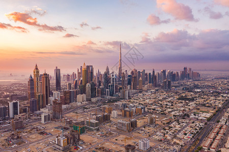 高层建筑和天线迪拜下城天线和高速公路阿拉伯联合酋长国或阿金融区和智能城市商业区日落时天梯和高楼大的BurjKhalifa空中观察背景