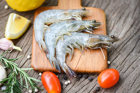 木制切板上新鲜虾配有食用海产品生虾的饲料草药和香图片