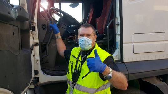 新冠的面罩和防护手套在卡车上携带面罩和防护手套的青年运输员图片