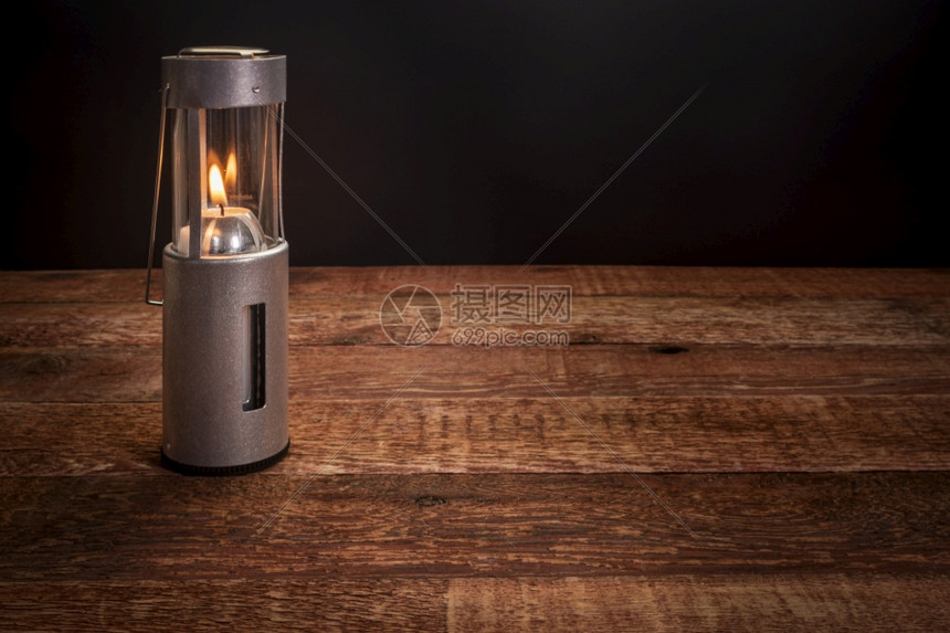 在黑暗中燃烧的灯笼在黑暗中烧一个生锈的木制野餐桌上复空间图片