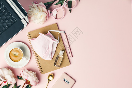 办公室桌平板面博客工作空间模型上面有咖啡计算机花朵面罩清洁剂和粉红色背景的女配件背景图片