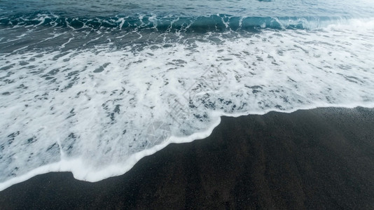蓝色海浪以黑火山沙子在海滩上滚动和破碎的美丽图像蓝色海浪以黑火山沙子在海滩上滚动和破碎的美丽图像图片