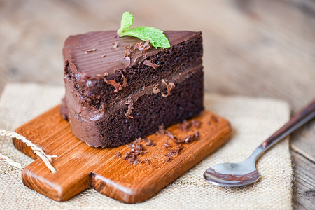 餐桌上的蛋糕巧克力甜点木制切板上一块蛋糕片配巧克力和薄荷叶图片
