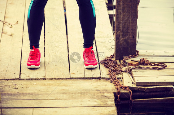 部分培训在户外积极运动的女孩在湖岸木码头上穿红鞋的双腿在木码头上穿红运动鞋的双腿图片