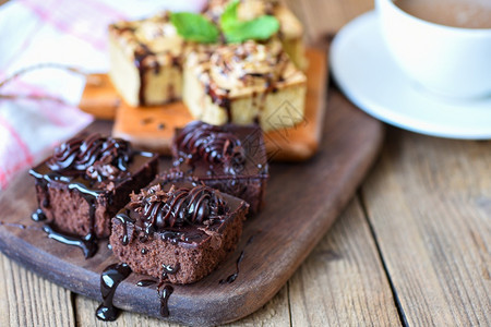 餐桌上的咖啡蛋糕甜点餐桌上木板背景的蛋糕巧克力切片配薄荷叶和早餐咖啡杯图片