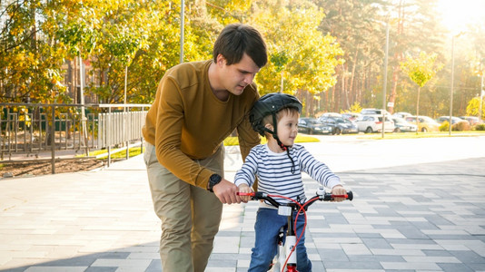 在阳光明媚的白天人和他儿子在城市街道骑自行车的肖像图片