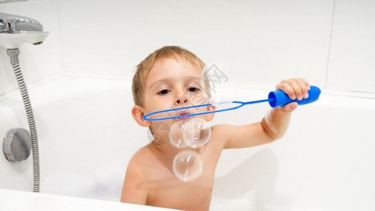 可爱男孩在洗澡时吹肥皂泡的肖像图片