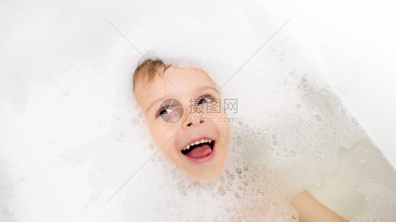 穿着肥皂泡沫的可爱小男孩有趣肖像图片