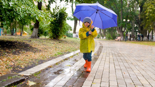 小男孩在下雨时公园走着伞小男孩在中公园走着伞小男孩在中走着伞小男孩在公园走着雨图片