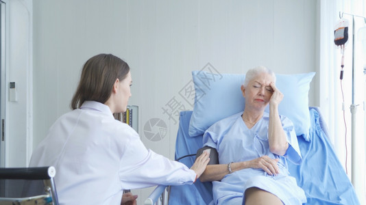 女医生在讨论关于检查医院病房的患有抑郁症老年病人的血压测试可悲消息时在医疗和概念上讲到图片