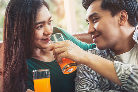 亚洲夫妇在客厅喝橙汁健康食物概念图片