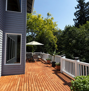 与季节花园一起在美丽的夏日家门口的木甲板庭院背景图片