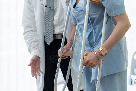 医生照顾院的拐杖病人理疗师和腿部受伤康复概念背景图片