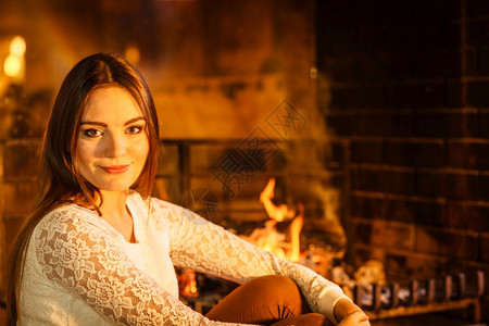 女人在壁炉里休息年轻女孩暖和家里冬天女人在壁炉里放松冬天回家图片