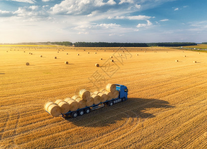 农业机械日落收割粮食作物之后的查封田地和干草堆顶层视图拖拉机在卡车上装载大量干草拖车图片