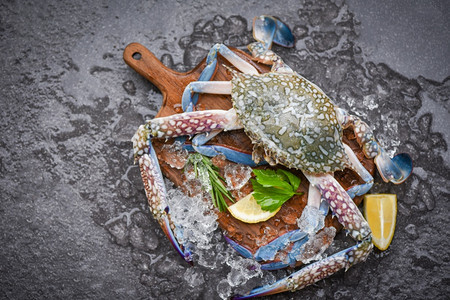新鲜生螃蟹配有柠檬迷迭香和生菜成分用于在市场冷冻海产食品蓝泳蟹的冰面上做熟食图片