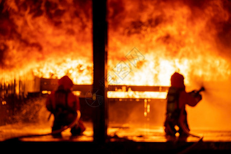 消防员使用水雾灭火器在大型建筑中使用灭火器与焰战斗消防员和工业安全灾害及公共服务概念摘要背景模糊图片