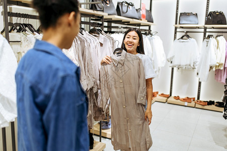 两个快乐的女孩在服装店中选择衣图片