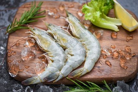 海产食品餐厅冰冻的生虾配有迷香成分药草和烹饪海鲜香料的木制剪板上新鲜虾图片