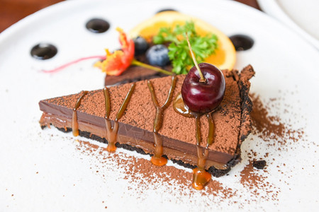 巧克力蛋糕焦糖和樱桃水果白色盘子关闭蛋糕切片高清图片
