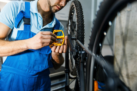 修理车间的自行修理人安装脚踏板修理自行车的机械师工场自行车修理人安装脚踏板图片