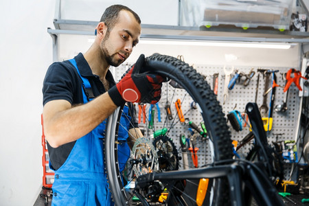 工场的自行车组装人安后轮穿制服修理自行车的机械师专业自行车修理服务间的自行组装人安轮图片