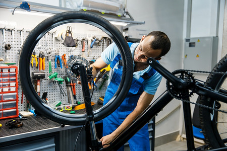 修理车间的自行修理男子设置刹车穿制服修理自行车的机械师专业自行车修理服务间的自行修理图片