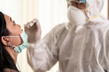 个人防护设备服检验科罗纳coronaviruscovid19的医务人员在全肢上通过鼻子擦拭对亚裔妇女进行检验新冠19检验保健概念图片