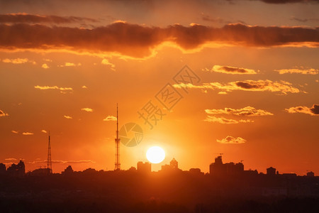 日落美丽时基辅市的轮廓建筑物与有太阳和红云的多彩橙色天空相对的中观察城市景中心背城地平线景色图片
