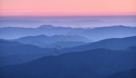 秋天日落时雾中山脊美丽的风景有雾山谷岩石森林红天在黄昏时蓝色钟坠落山的空中景象顶端风自然背图片