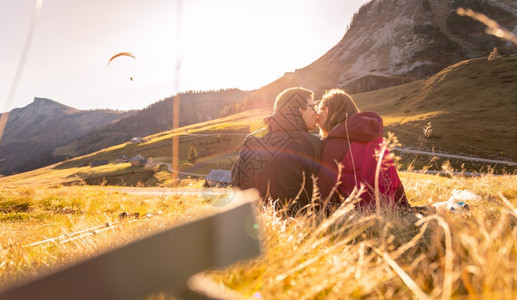 穿着运动服的夫妇享受山上日落坐在地上享受风景奥地利阿尔卑斯背景图片