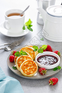 蒂凡尼的早餐奶油芝士煎饼甜卷和浆果酱新鲜草莓在早餐桌上背景