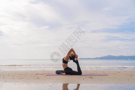 一名在瑜伽班俱乐部的亚洲妇女在自然海滩和滨户外从事运动和娱乐概念方面的锻炼和瑜伽图片