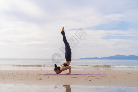 一名在瑜伽班俱乐部的亚洲妇女在自然海滩和滨户外从事运动和娱乐概念方面的锻炼和瑜伽图片