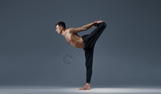 雄瑜伽使巴朗氏菌处于一种困难的姿势灰色背景强健的男子在做瑜伽运动麻风病训练高度集中健康的生活方式雄瑜伽使巴朗氏菌处于一种困难的姿图片