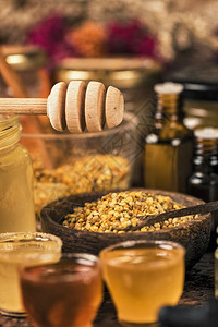 不同种类的蜂蜜花粉蛋白和桌上的木制蜂蜜薄饼和制品图片