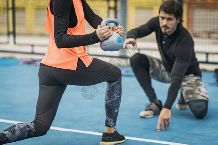 与年轻女一起工作的个人健身教练在户外做小叮当锻炼与女客户Kettlebell锻炼户外做个人教练图片