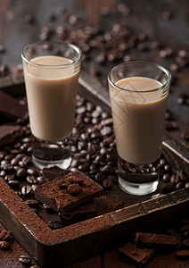 爱尔兰奶油卷饼装在木质托盘上配有咖啡豆和黑巧克力粉深木本底涂有黑巧克力图片